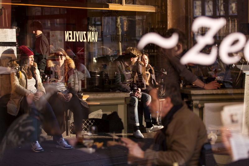 © Reuters. Visitors of a local cafe are reflected in a window in Amsterdam