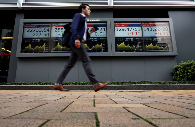 © Reuters. A passerby walks past an electronic boards Japan's Nikkei average, the Dow Jones Industrial Average and foreign exchange rates outside a brokerage in Tokyo