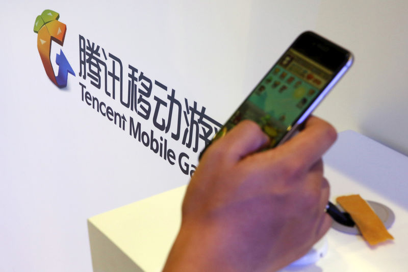 © Reuters. FILE PHOTO: Visitor plays a game on a smartphone at Tencent's exhibition booth at the Global Mobile Internet Conference (GMIC) 2015 in Beijing