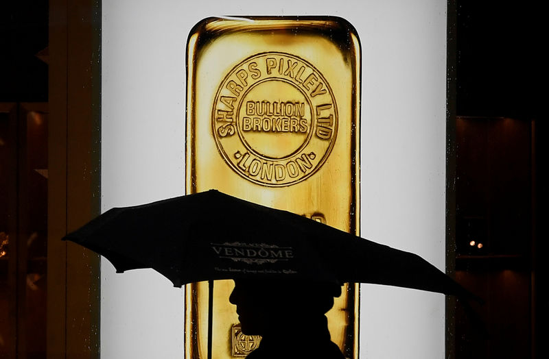 © Reuters. FILE PHOTO: A pedestrian walks past a window displaying a representation of a gold bar at a bullion broker in Piccadilly, London, Britain