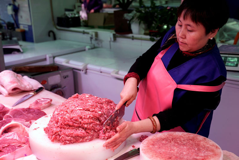 © Reuters. FILE PHOTO: A vendor prepares pork for sale at a market in Beijing