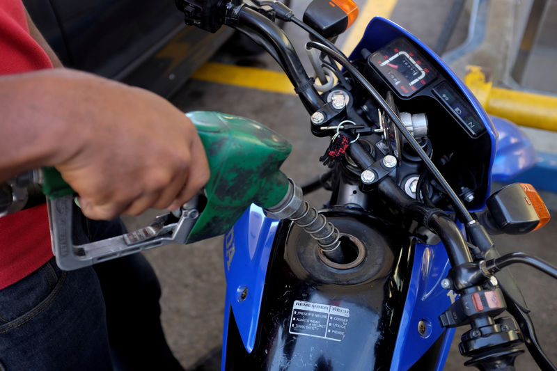 © Reuters. FILE PHOTO: A gas station worker pumps fuel into a motorbike at a gas station of the Venezuelan state-owned oil company PDVSA in Caracas