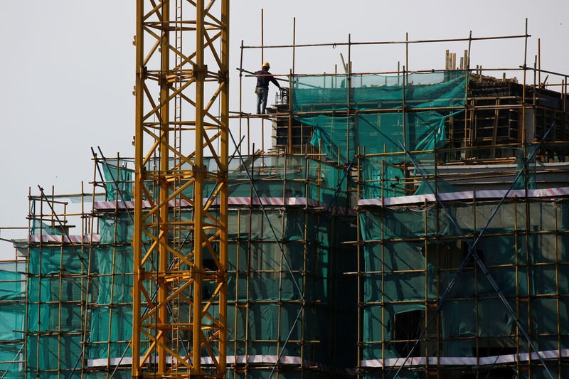 © Reuters. A man works on the scaffolding surrounding an apartment block at a construction site in Beijing