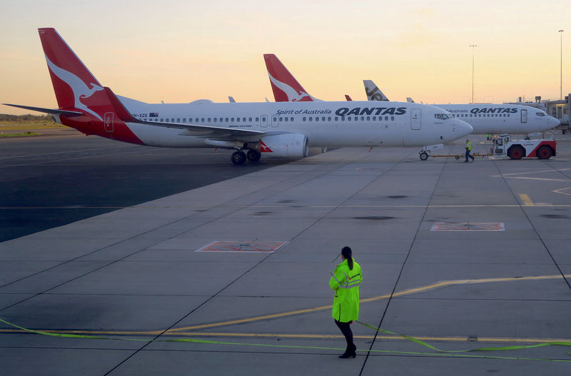 © Reuters. FILE PHOTO: Workers are seen near Qantas Airways' Boeing 737-800 aircraft on the tarmac at Adelaide Airport