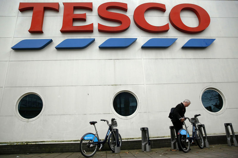 © Reuters. A man unlocks a bicycle outside a branch of Tesco supermarket  in London