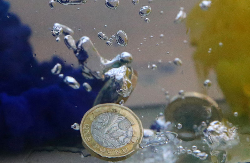 © Reuters. UK pound coins plunge into water coloured with the European Union flag colours in this illustration picture