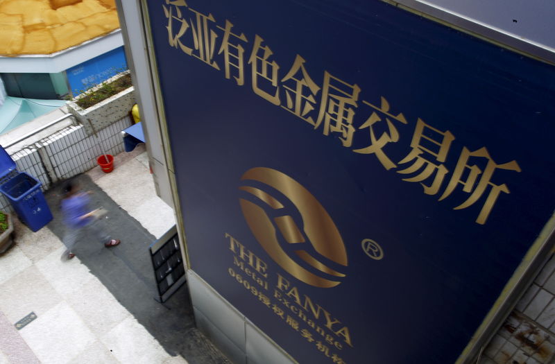 © Reuters. A woman walks past the company logo of the closed exchange centre of the Fanya Metal Exchange in downtown Kunming