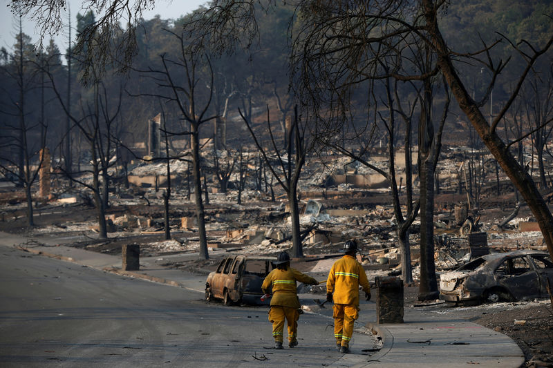 © Reuters. FILE PHOTO: Firefighters walk in a neighborhood destroyed by the Tubbs Fire in Santa Rosa, California