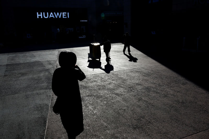 © Reuters. FILE PHOTO - People walk past a Huawei shop in Beijing