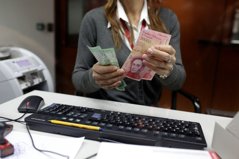 © Reuters. A bank teller counts bolivar banknotes at a Banco de Venezuela branch in Caracas