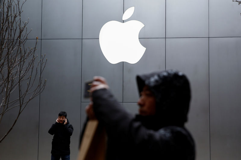 © Reuters. FILE PHOTO - People use their phones outside an Apple store in Beijing