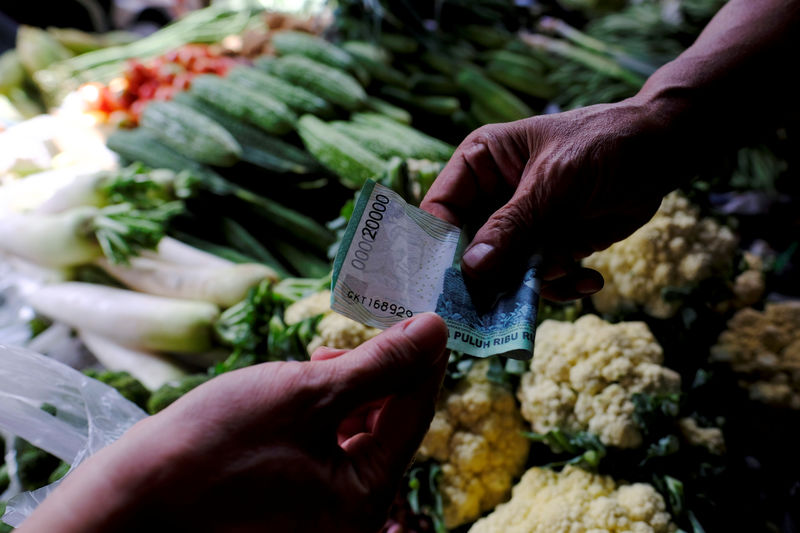 © Reuters. A vegetable vendor takes money from customer at a morning market in Jakarta