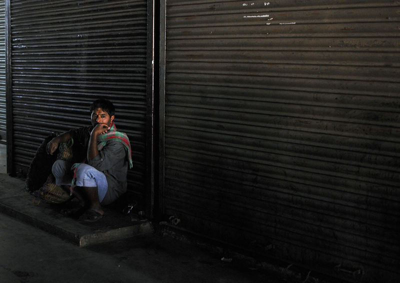 © Reuters. A daily wage worker waits for employment in front of closed shops at a market in the southern Indian city of Bengaluru