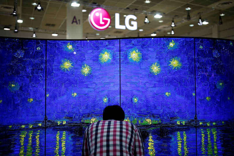 © Reuters. FILE PHOTO - A man examines LG Electronics' double-faced and curved OLED TV during Korea Electronics Show 2016 in Seoul