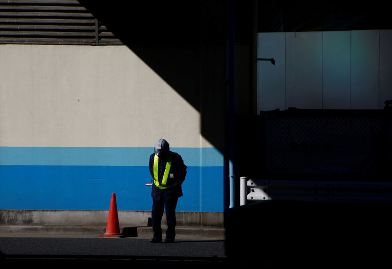 © Reuters. FILE PHOTO - A worker stands in front of an entrance of a construction site of a commercial building at a business district in Tokyo