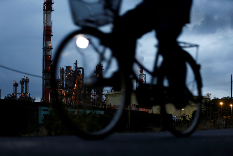 © Reuters. FILE PHOTO - A bicycle rider rides past a factory at Keihin industrial zone in Kawasaki