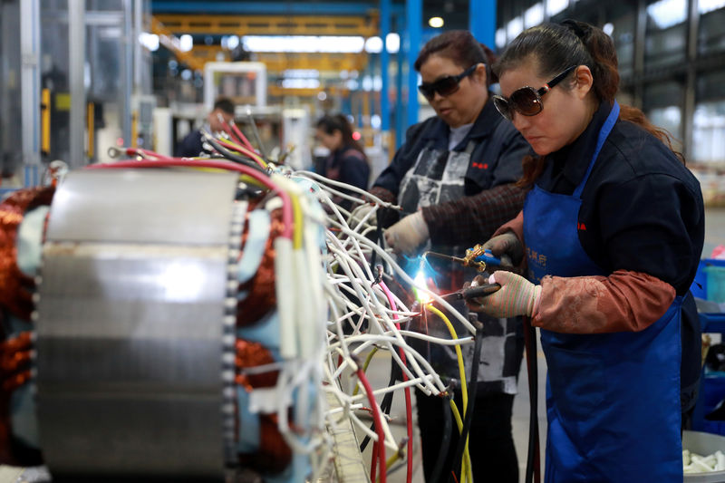 © Reuters. Women wearing sunglasses work at a production line manufacturing electric machine parts at a factory in Luan, Anhui