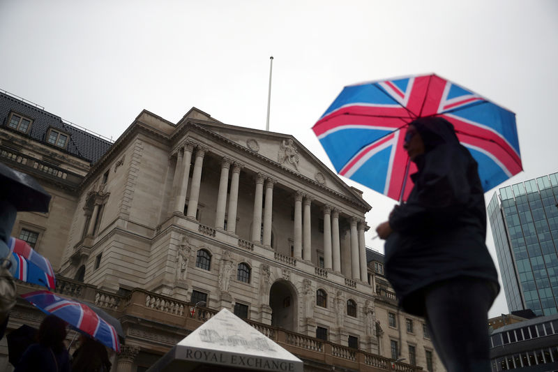 © Reuters. A pedestrian shelters under an umbrella in front of the Bank of England, in London