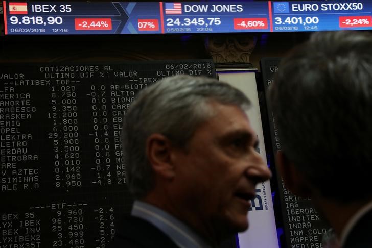 © Reuters. Operadores cerca de la pantalla con las cotizaciones de las compañías  españolas en la Bolsa de Madrid