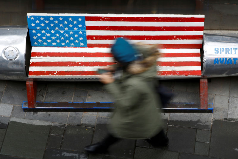 © Reuters. FILE PHOTO: Woman walks past a bench painted in the colours of the U.S. flag outside a clothing store in Beijing