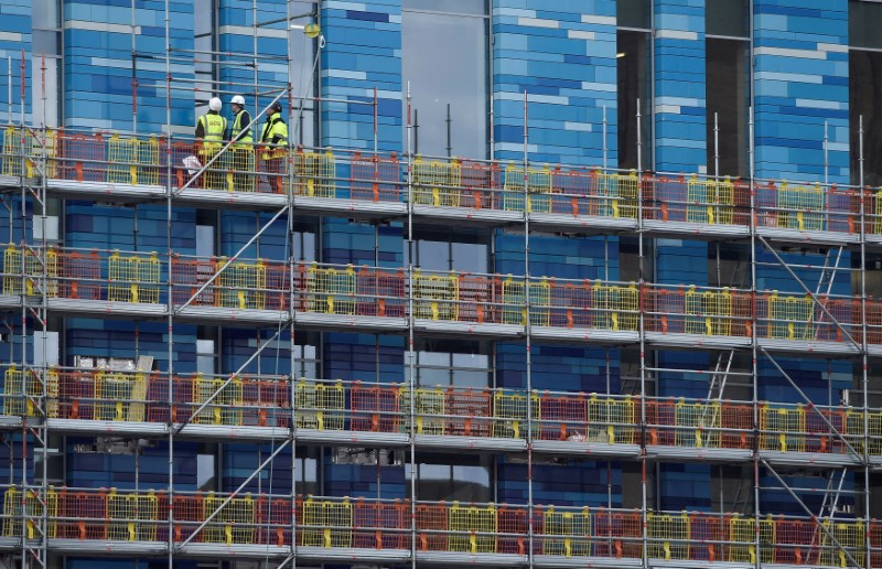© Reuters. Workers stand on scaffolding at a residential building in London