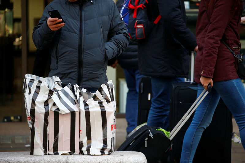 © Reuters. FILE PHOTO - A shopper stands behind his shopping, contained in plastic bags, in the West End, in London