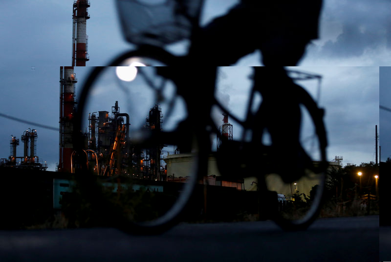 © Reuters. FILE PHOTO - A bicycle rider rides past a factory at Keihin industrial zone in Kawasaki