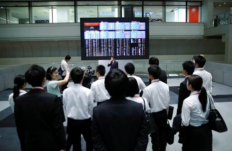 © Reuters. FILE PHOTO - Visitors look at an electronic stock quotation board at the TSE in Tokyo