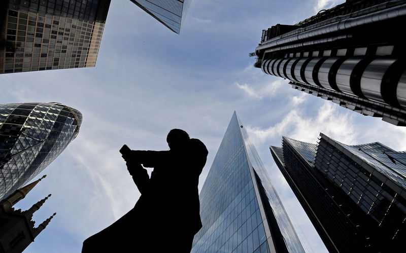 © Reuters. Un trabajador mira su teléfono mientras camina por la City de Londres
