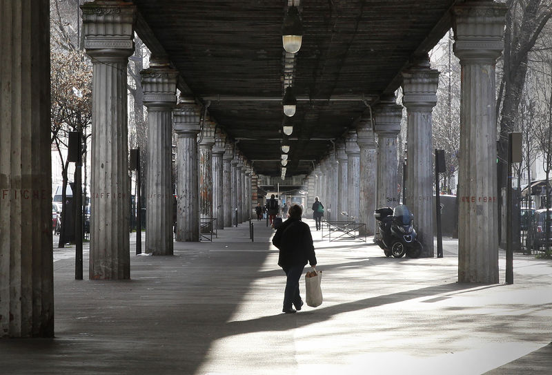 © Reuters. An early morning shopper walks under the line 6 Metro train overpass on Boulevard de Grenelle in Paris