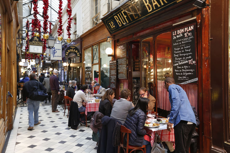 © Reuters. FILE PHOTO:  People sit at tables as they have lunch outside bistros in a covered passageway, the Passage des Panoramas, in Paris