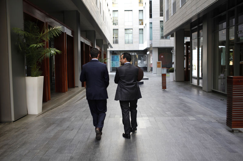 © Reuters. Men walk past buildings at the Dubai International Financial Center in Dubai