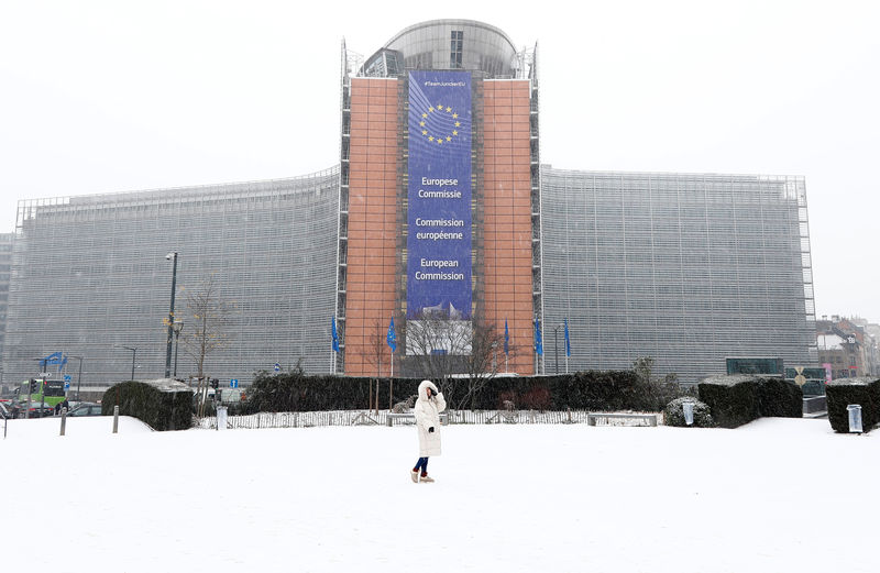 © Reuters. A woman poses in front of the EU Commission headquarters as snow falls in Brussels