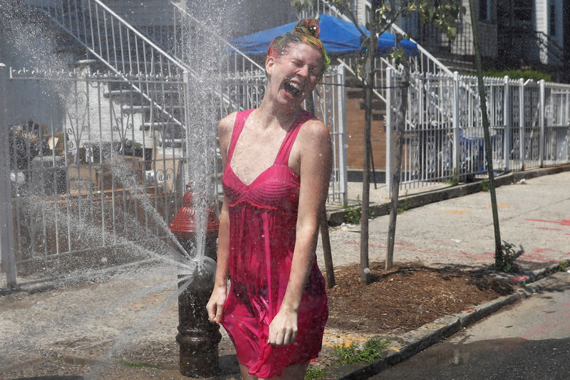 © Reuters. Mulher se refresca em meio a onda de calor em hidrante em Nova York