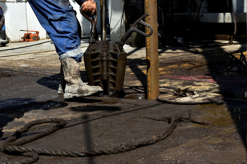 © Reuters. A member of a drilling crew prepares to place a collar around drill pipe on an oil rig in the Permian Basin near Wink