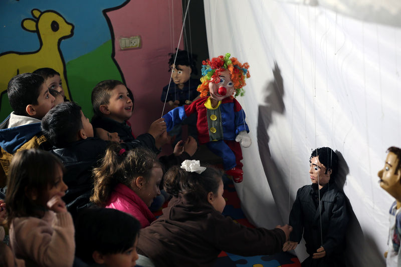 © Reuters. Un titiritero logra sacar sonrisas a niños de Gaza con sus marionetas