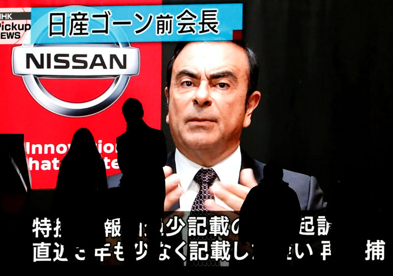 © Reuters. FILE PHOTO: Passersby are silhouetted as a huge street monitor broadcasts news reporting ousted Nissan Motor chairman Carlos Ghosn's indictment and re-arrest in Tokyo