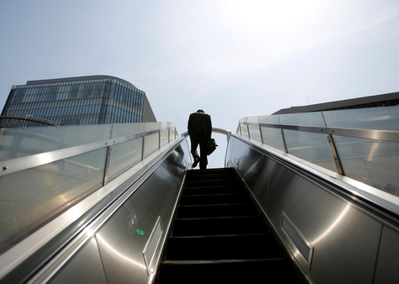 © Reuters. FILE PHOTO - A businessman rides on an escalator in Tokyo's business district