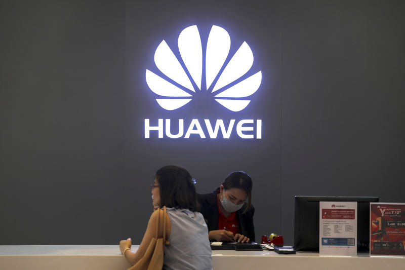 © Reuters. FILE PHOTO - A woman sits next to a salesperson at a Huawei shop in Bangkok, Thailand