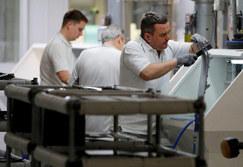 © Reuters. FILE PHOTO: A Bentley Motors employee works on a piece of a dashboard trim inside their factory in Crewe