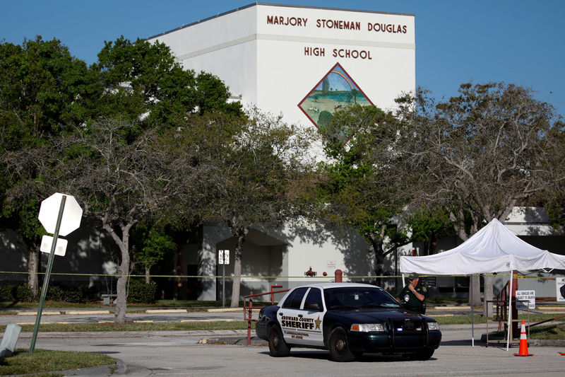 © Reuters. FILE PHOTO: Police officer Jamie Rubenstein stands guard in front of the Marjory Stoneman Douglas High School, after the police security perimeter was removed, following a mass shooting in Parkland