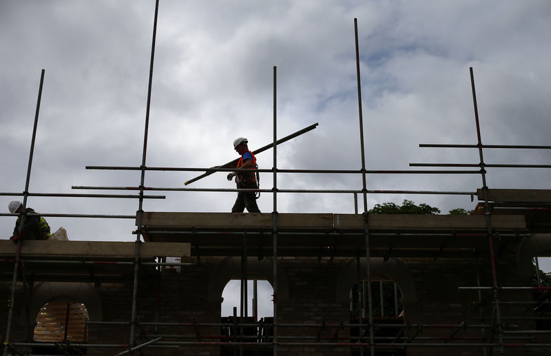 © Reuters. FILE PHOTO: A builder assembles scaffolding as he works on new homes in south London