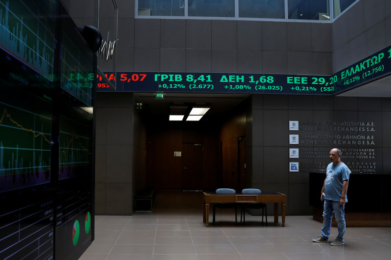 © Reuters. A man stands under a stock ticker showing stock options inside the Athens stock exchange building in Athens