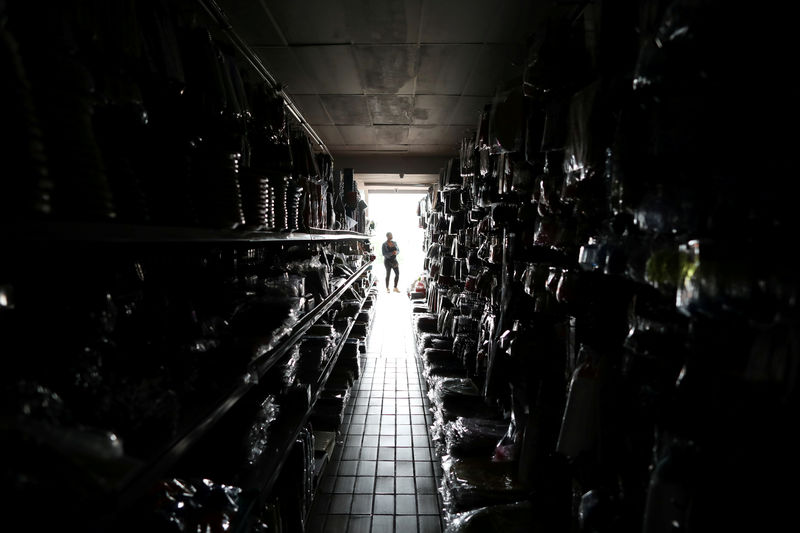© Reuters. FILE PHOTO: A shop assistant stands in the doorway of a party goods store during an electricity load-shedding blackout in Johannesburg