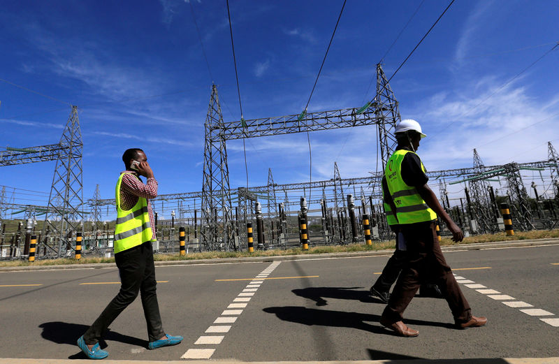 © Reuters. FILE PHOTO: Kenya Electricity Generating Company workers walk past the pylons of high-tension electricity power lines at the Olkaria II Geothermal power plant near the Rift Valley town of Naivasha