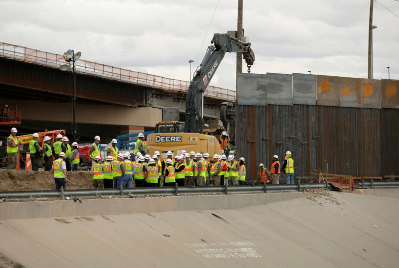 © Reuters. Workers and U.S border patrol officers stand next to an excavator working in a section of the new wall between El Paso and Ciudad Juarez