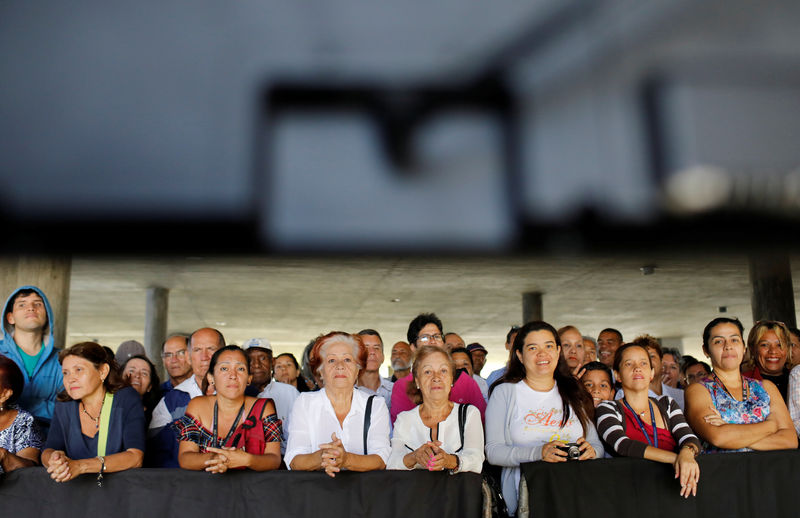 © Reuters. People look at the broadcast of the meeting of Venezuelan opposition leader Juan Guaido, who many nations have recognized as the country's rightful interim ruler, with workers in Caracas