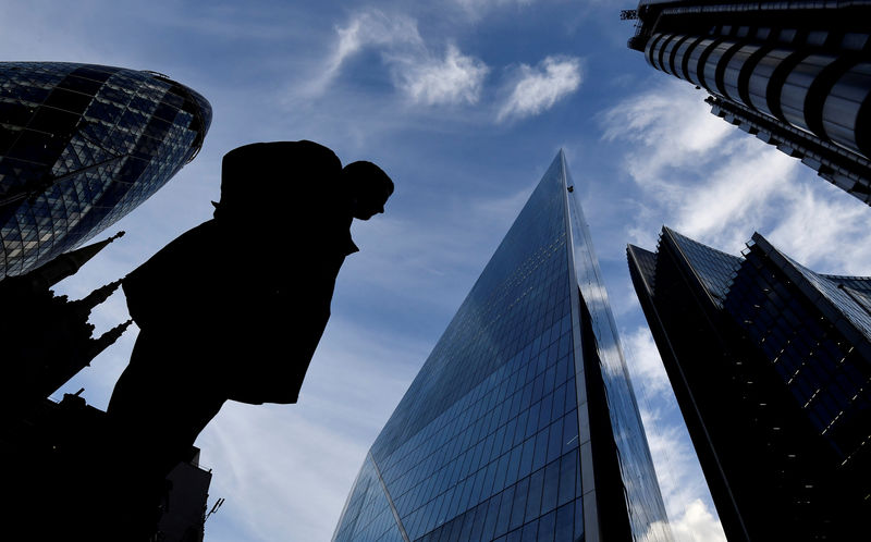 © Reuters. FILE PHOTO: A man walks past The Gherkin and other office buildings in the City of London