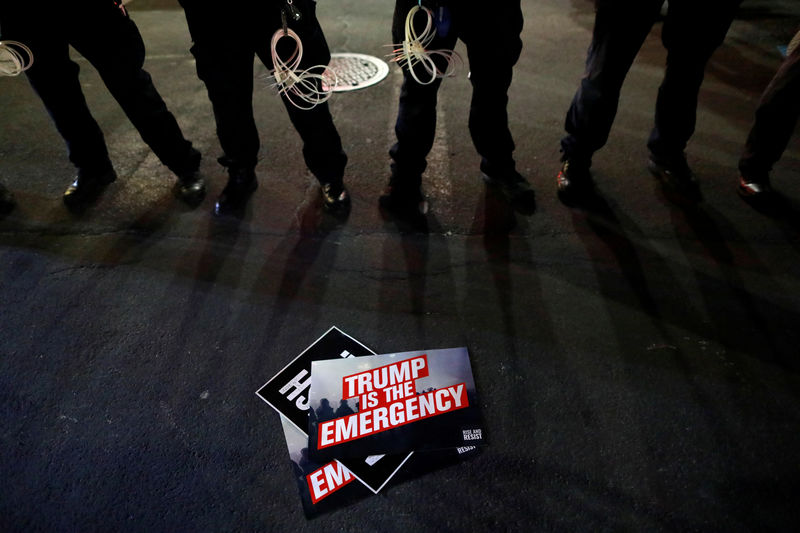 © Reuters. A sign is seen on the street in front of a row of police during a protest against U.S. President Donald Trump's declaration of a national emergency to build a border wall, outside Trump International Hotel & Tower in Manhattan, New York