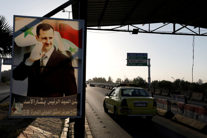 © Reuters. FILE PHOTO: A poster of Syrian President Bashar al-Assad is seen on the main road to the airport in Damascus